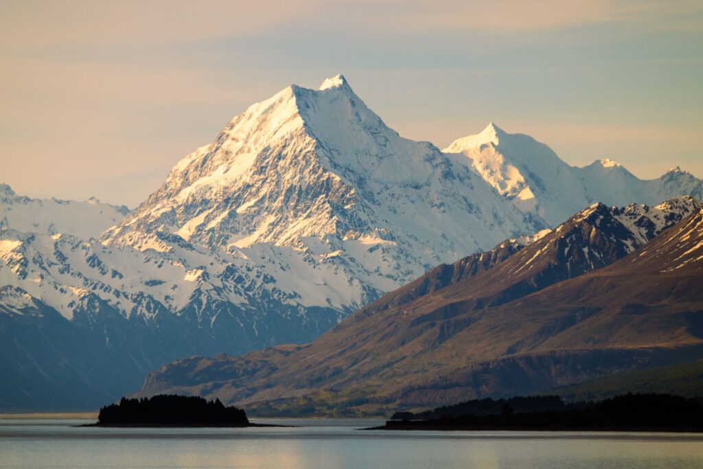 Breathtaking view of snow-capped Aoraki Mount Cook and Lake Pukaki in New Zealand at sunset.