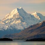 Breathtaking view of snow-capped Aoraki Mount Cook and Lake Pukaki in New Zealand at sunset.