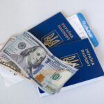 Close-up view of Ukrainian passports with US dollar bills, symbolizing travel readiness.