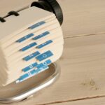 A close-up of a traditional Rolodex with alphabet tabs on a wooden desk.
