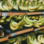 Close-up of fresh bananas stacked on grocery store shelves with price tags visible.