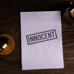 Close-up of legal document stamped 'Innocent' beside a gavel on a wooden desk.