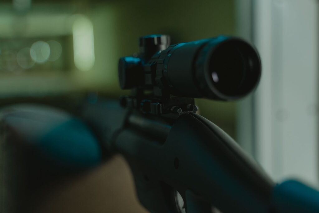 Focused image of a rifle with a mounted scope in a controlled environment.