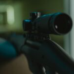 Focused image of a rifle with a mounted scope in a controlled environment.