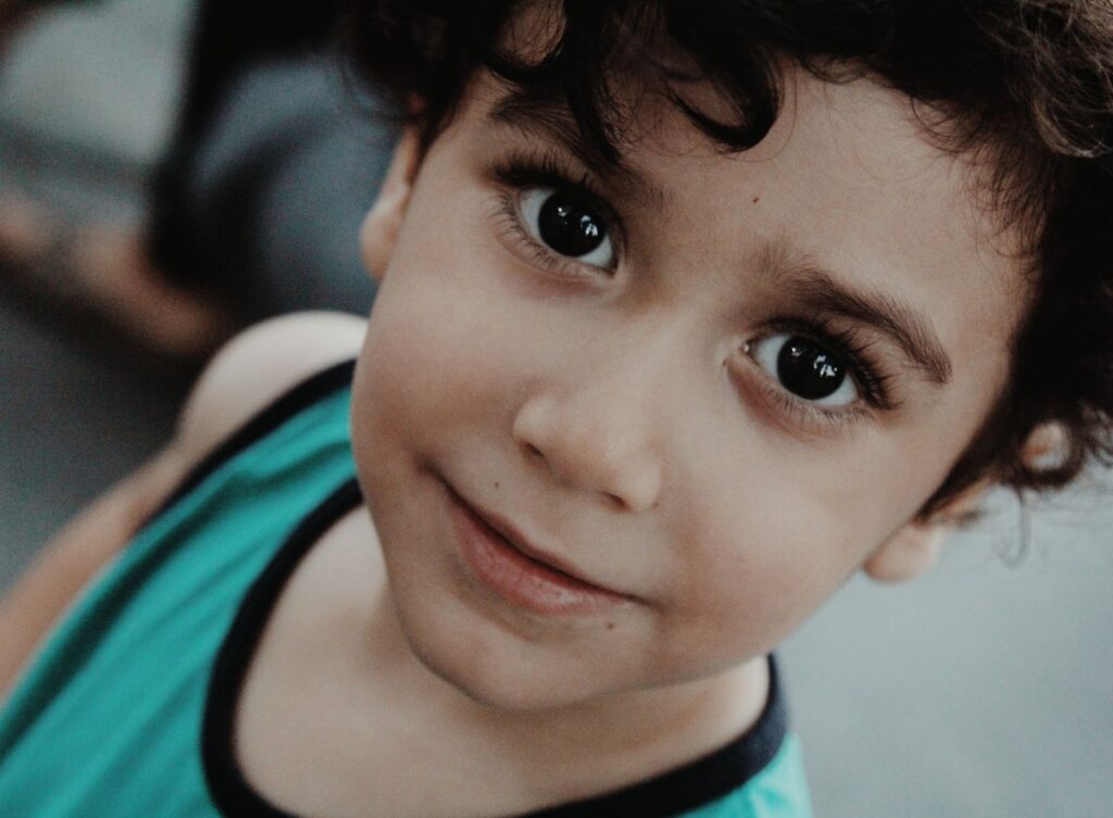 Adorable close-up of a smiling young boy with captivating eyes.