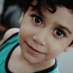 Adorable close-up of a smiling young boy with captivating eyes.