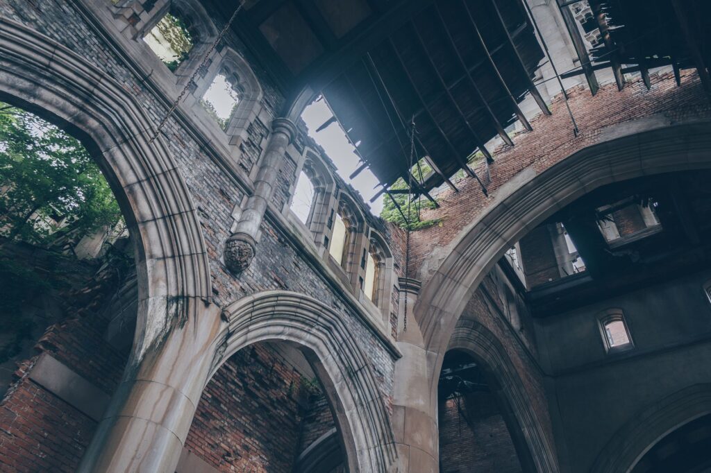 A low angle view of an abandoned church interior with stunning arches and deteriorating walls.