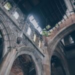 A low angle view of an abandoned church interior with stunning arches and deteriorating walls.