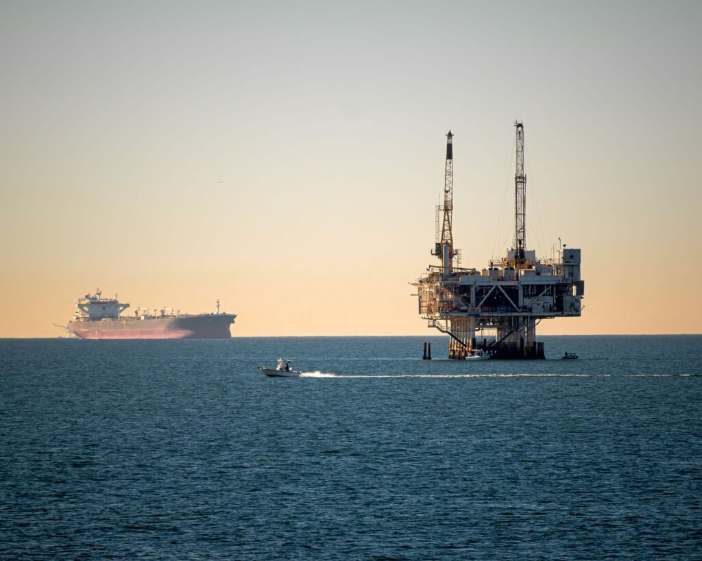 Offshore oil platform with container ship in tranquil sea during daytime.