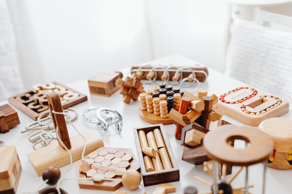 A variety of handcrafted wooden puzzles and games placed on a white table.
