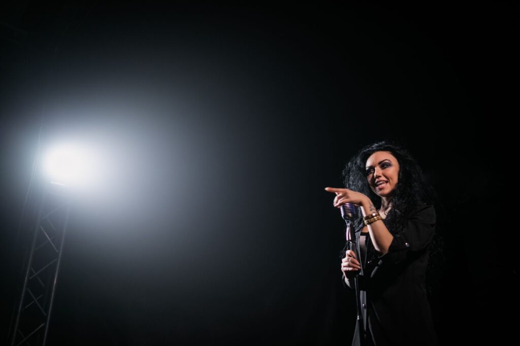 Live performance of a female singer on stage under a spotlight, exuding energy and charisma.