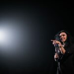 Live performance of a female singer on stage under a spotlight, exuding energy and charisma.