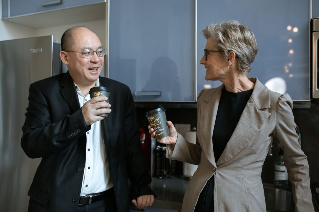 Two business professionals sharing a coffee break in a modern office kitchen.