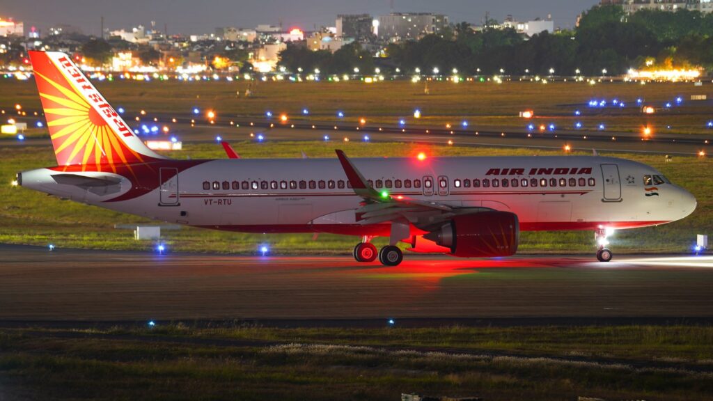 Air India Airbus A321 ready for takeoff on illuminated runway at night.