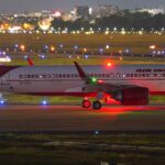 Air India Airbus A321 ready for takeoff on illuminated runway at night.
