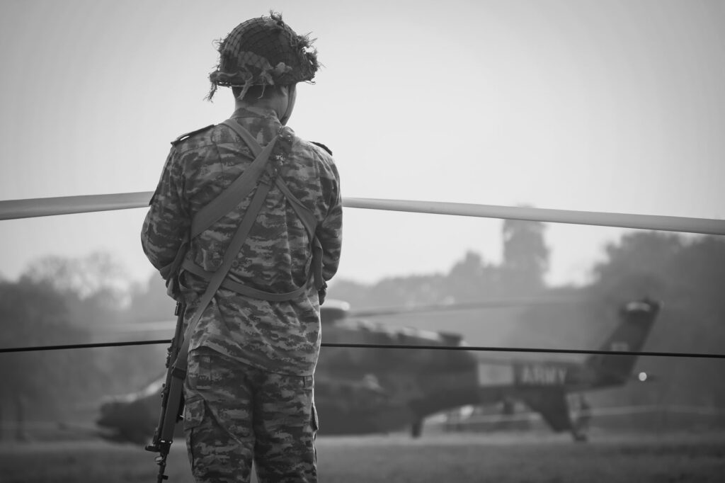 Indian Army soldier in camouflage watches over military helicopter at Kolkata airfield.