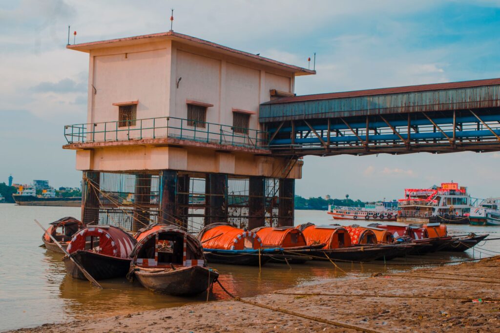 Wooden boats moored on the Ganges Riverbank next to a pier building in India.