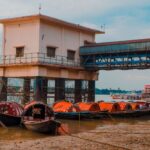 Wooden boats moored on the Ganges Riverbank next to a pier building in India.