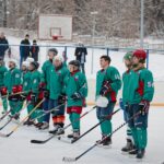 Group of male ice hockey players standing in a row during a winter match outdoors.