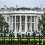 A classic view of the White House in Washington DC with lush greenery and fountains.