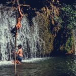Boys enjoying a summer day climbing near a waterfall in Thailand.