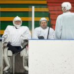 Hockey players in uniforms sitting on the bench during a game pause inside the ice rink.
