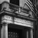 Black and white photo of the New York Stock Exchange facade with USA flag.