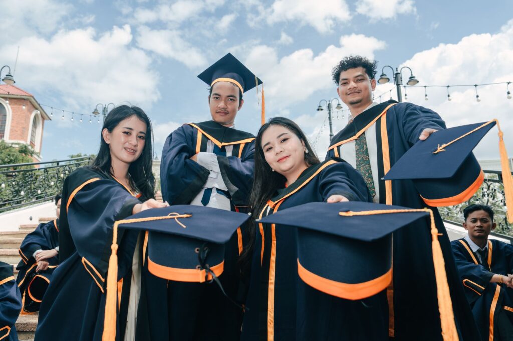 A group of young adults celebrating their graduation with caps and gowns outdoors.