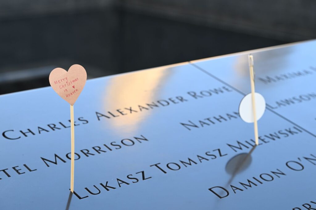 Emotional tribute with a heart card at a memorial displaying engraved names.