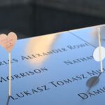 Emotional tribute with a heart card at a memorial displaying engraved names.